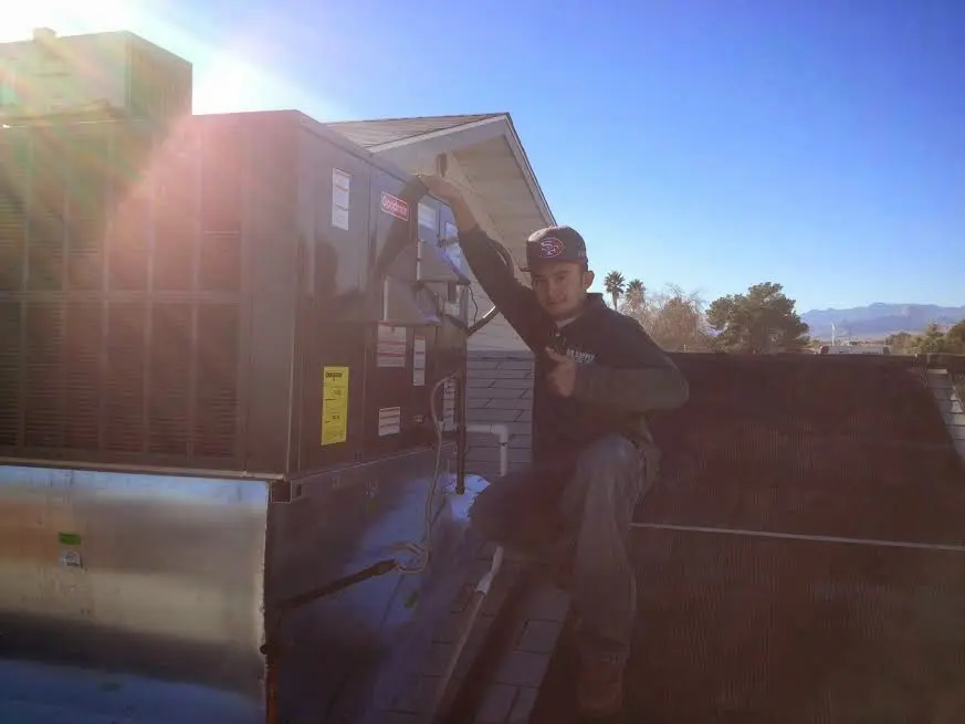 HVAC technician performing AC Tune-Up on a rooftop unit in Malone
